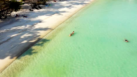 A-partial-orbit-aerial-drone-shot-of-tourists-who-are-swimming-and-sunbathing-in-Shark-Bay-beach-in-the-island-of-Kho-Tao-in-Surat-Thani-province-in-Thailand