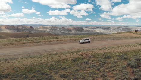Aerial-orbit-and-reveal-of-car-on-dirt-road-at-Pilot-Butte-Wild-Horse-Scenic-Loop,-Wyoming-USA