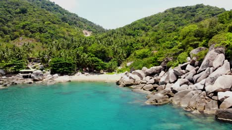 Panning-from-right-to-the-left-side-of-the-frame-on-a-secluded-rocky-beachfront-of-Ao-Hin-Wong,-a-scenic-bay-with-crystal-blue-waters-on-the-east-side-of-Koh-Tao-island-in-Thailand