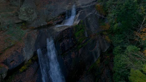 Drone-flying-over-a-massive-waterfall-in-the-mountains-of-autumn-colors-in-the-afternoon