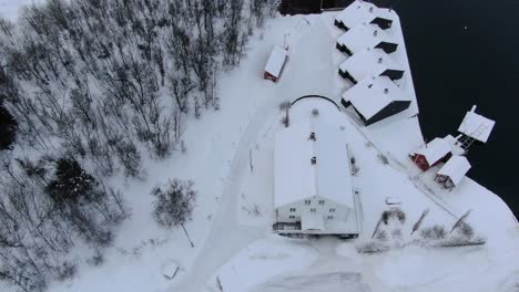Drone-view-in-Tromso-area-flying-over-a-hotel-in-Finnsnes-in-winter-and-showing-the-sea-next-to-the-snowy-town-with-a-hotel-in-Norway