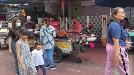 Street-food-vendors-selling-and-packing-food-for-customers-and-tourists-sauntering-in-Yaowarat-Chinatown,-Bangkok,-Thailand