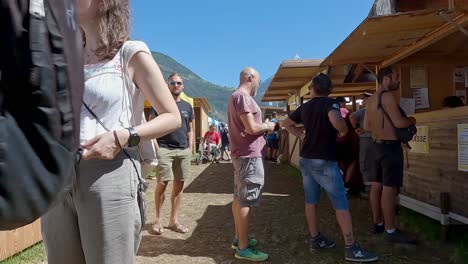 South-Tyrolean-Medieval-Games,-people-queueing-in-front-of-a-food-stall-whils-others-walk-past-them