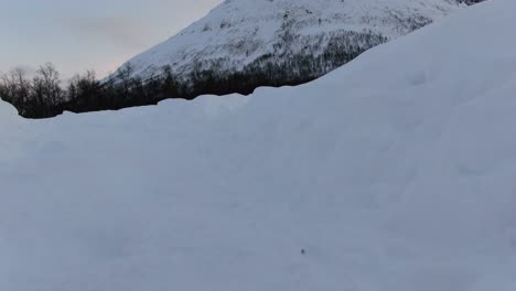 Vista-De-Drones-Sobre-Las-Montañas-De-Tromso-En-Invierno-Llenas-De-Nieve-Mostrando-Un-Bosque-Levantándose-Del-Suelo-En-Noruega