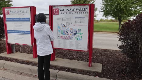 Frau-Schaut-Auf-Eine-Karte-Auf-Dem-Campus-Der-Saginaw-Valley-State-University-Im-University-Center,-Michigan,-Mit-Einem-Gimbal-Video,-Das-Hinter-Ihr-Läuft