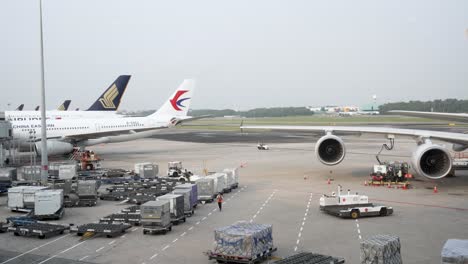 Mit-Blick-Auf-Geparkte-Gepäckcontainer-Und-Geparkte-Flugzeuge-Neben-Dem-Terminalgebäude-Am-Flughafen-Changi,-Singapur