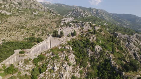 Fortifications-of-Kotor-in-Montenegro,-aerial-orbit-on-a-sunny-summer-day