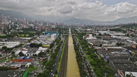 Medellin-Colombia-Aerial-v14-flyover-river-capturing-cityscape-of-riverside-neighborhoods,-busy-highway-and-street-traffics-and-Poblado-metro-train-station---Shot-with-Mavic-3-Cine---November-2022