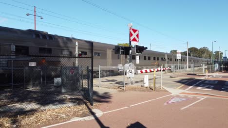 Silver-rail-cars-of-the-Indian-Pacific-passenger-train-passing-through-Guildford-level-crossing,-Perth