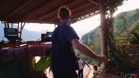 DJ-Realiza-Gestos-De-Agradecimiento-Tocando-Su-Corazón-Con-Las-Manos-En-Guatemala-Actuando-En-Un-Escenario-Con-Vistas-Al-Lago-De-Atitlán-Y-Sus-Volcanes.