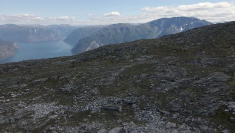 Aerial-orbiting-shot-of-riding-mountain-biker-on-rocky-slope-of-Mountain-and-fjord-of-Norway-in-the-valley
