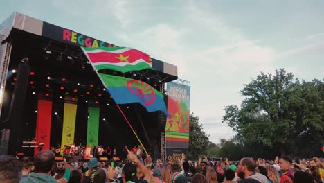Fan-Schwenkt-Die-Flagge-Von-Roma-Und-Surinam-In-Zeitlupe-Beim-Reggae-Festival-Während-Der-Aufführung