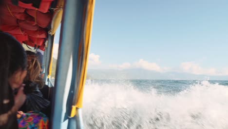 Pan-from-left-to-right-in-water-taxi-full-of-people-going-at-speed-on-lake,-lifejackets-visible