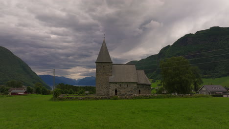Historic-Hove-stone-church-in-countryside-under-ominous-sky,-Vik