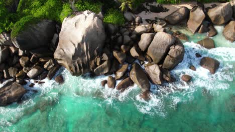 Bird-eye-drone-shot-of-near-north-east-point-beach,-huge-rock-boulders,-white-sandy-beach-and-turquoise-water,-Mahe-Seychelles-60fps