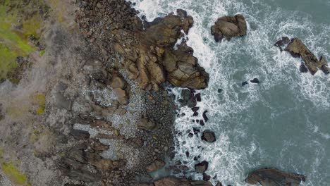 Rising-and-turning-aerial-view-of-wild,-choppy-Tasman-Sea-with-white-water-waves-against-rugged,-rocky-coastline-at-Cape-Foulwind-on-West-Coast,-South-Island-of-New-Zealand-Aotearoa