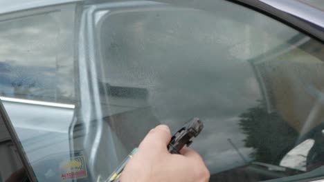 Spraying-glass-cleaner-onto-car-window