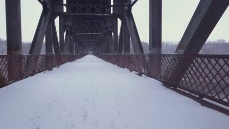 Snowing-winter-POV-along-unused-and-abandoned-steel-truss-bridge-deck