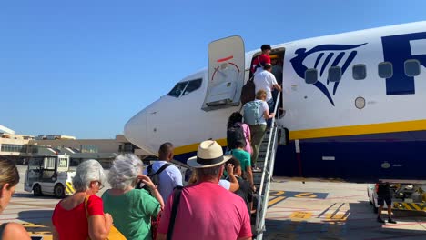 Gente-Parada-Y-Abordando-Lentamente-Un-Gran-Avión-Boeing-De-Ryanair-En-El-Aeropuerto-Internacional-De-Málaga-En-Un-Día-Soleado-En-España,-Vacaciones-De-Verano,-Toma-Estática-De-4k