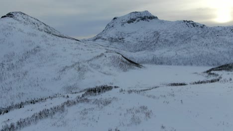 Vista-De-Drones-En-La-Zona-De-Tromso-En-Invierno-Volando-Sobre-Una-Montaña-Nevada-En-Segla,-Noruega-Con-árboles-Sin-Hojas