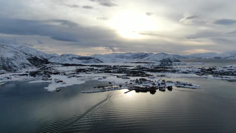 Vista-De-Drones-En-La-Zona-De-Tromso-En-Invierno-Volando-Sobre-Islas-Nevadas-Rodeadas-Por-El-Mar-Y-Molinos-De-Viento-En-La-Montaña-En-Noruega