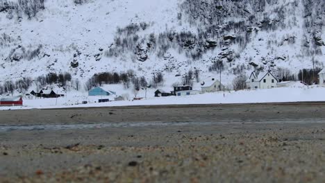 Tromso-Gebiet-Im-Winter,-Ebenerdiger-Blick-Auf-Den-Strand-Mit-Verschneiter-Landschaft-Und-Einem-Bach,-Der-In-Norwegen-Fließt