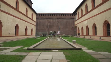 Innenhof-Des-Sforzesco-Schloss-Mit-Wasserbecken-Und-Menschen,-Die-In-Der-Nähe-Der-Verteidigungsmauer-Herumlaufen