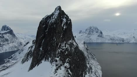 Drone-view-in-Tromso-area-in-winter-flying-over-a-snowy-mountain-showing-Segla-rocky-peak-in-Segla,-Norway