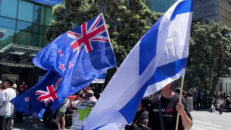Flag-of-Israel-and-New-Zealand-held-by-protestors,-slow-motion-closeup