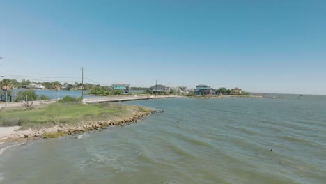 An-aerial-establishing-shot-of-the-Galveston-Bay-coastline-and-waterfront-homes-under-blue-skies-and-sunshine-along-Todville-Rd