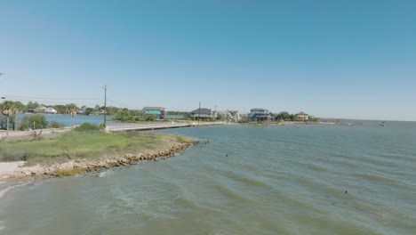 Una-Toma-Aérea-De-Establecimiento-De-La-Costa-De-La-Bahía-De-Galveston-Y-Las-Casas-Frente-Al-Mar-Bajo-Un-Cielo-Azul-Y-El-Sol-A-Lo-Largo-De-Todville-Rd.