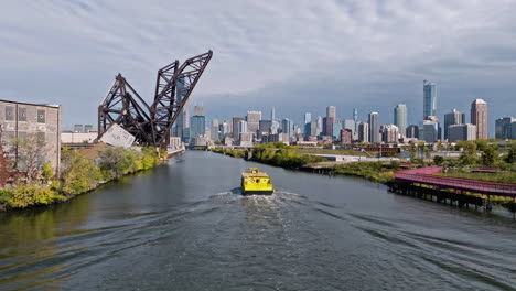 Aerial-view-following-a-watertaxi-on-the-south-branch-of-the-Chicago-river,-fall-day-in-USA