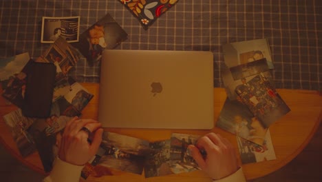 Mann-Tippt-Auf-Der-Tastatur-Eines-Apple-Laptops-Und-Schließt-Sie,-Daneben-Familienfotos