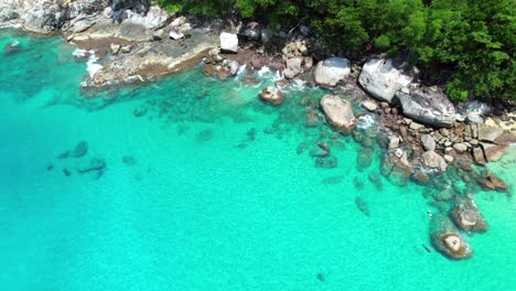 Drone-video-of-4-people-snorkelling-near-huge-granite-stones,-white-sandy-beach,-turquoise-transparent-Indian-ocean-water,-Mahe,-Seychelles-30fps-1