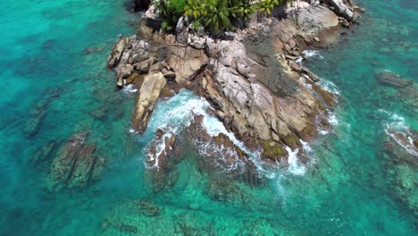 Bird-eye-drone-video-of-huge-granite-stones-near-the-Indian-ocean,-turquoise-transparent-water-and-crushing-waves,-Mahe,-Seychelles-30fps