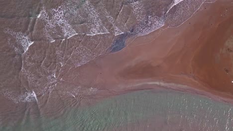 Luftdrohnenaufnahme-Von-Flachen-Wellen,-Die-Auf-Eine-Wunderschöne-Orangefarbene-Sandbank-Oder-Untiefe-Streichen
