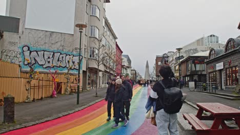Tilt-down-to-tourists-making-photo's-and-walking-around-Rainbow-Street-in-Reykjavik,-Iceland