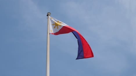 Philippine-flag-waving-in-the-air-with-the-blue-skies-as-it-background,-inside-the-Philippine-embassy-in-Bangkok,-Thailand