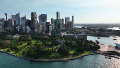Vista-Aérea-De-La-ópera-De-Sydney-Y-Los-Jardines-Botánicos-Reales-Con-Rascacielos-Detrás-En-Sydney,-Australia