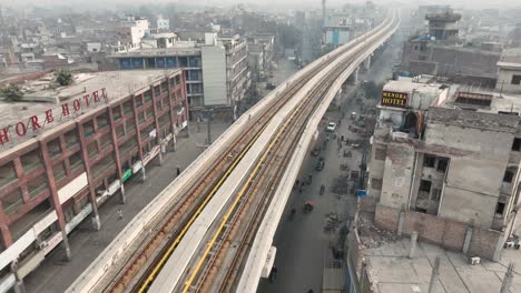 Vuelo-Aéreo-Sobre-La-Vía-Del-Metro-Naranja-Vacía-Al-Lado-Del-Edificio-Del-Hotel-De-Lahore