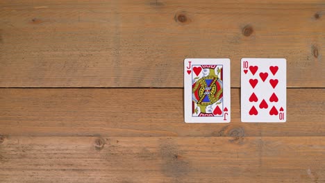 Eine-Person-Legt-Einen-Royal-Flush-Mit-Herzen-Auf-Einen-Holztisch,-Um-Dem-Zuschauer-Beizubringen,-Wie-Man-Poker-Spielt