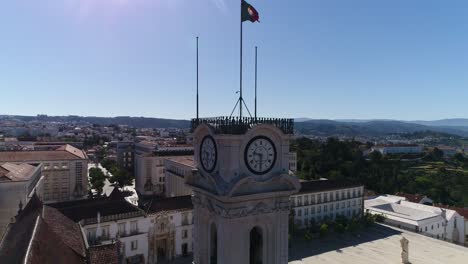 Coimbra-aerial-view-of-the-clock-tower-of-university-with-Portugal-flag-drone-footage-of-the-old-city-town