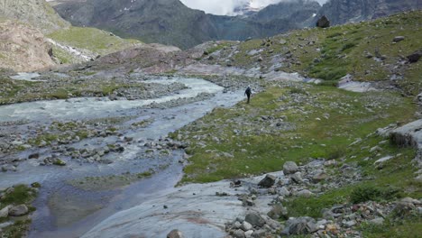 Caminante-Caminando-A-Través-De-Un-Río-Cerca-Del-Glaciar-Fellaria