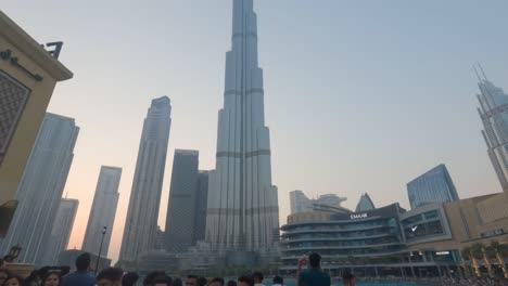 Fesselnder-Dubai-Brunnen-Wassertanz-Unter-Dem-Goldenen-Sonnenuntergang-Im-Dubai-Mall,-Mit-Dem-Ikonischen-Burj-Khalifa-Im-Hintergrund