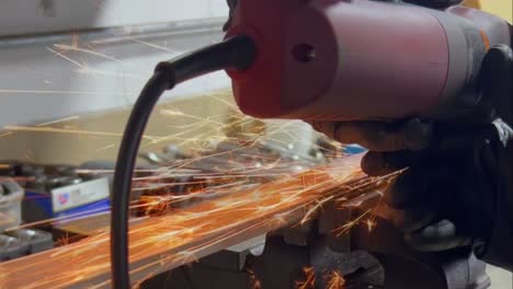 A-close-up-of-a-person-using-a-powered-metal-saw-to-cut-a-screw,-causing-orange-sparks-to-fly