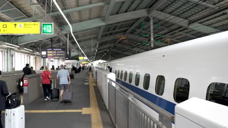 Reisende-Mit-Koffern-Laufen-Am-Bahnsteig-Neben-Dem-Stationären-Hochgeschwindigkeitszug-Am-Bahnhof-Shin-Kobe-Entlang