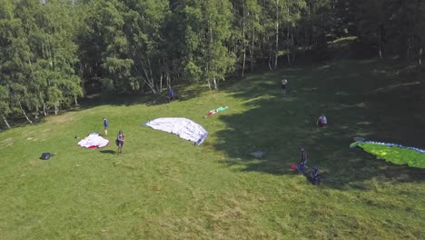 Paragliders-standing-on-the-side-of-a-hill,-waiting-for-good-flight-conditions