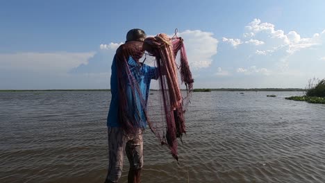 Watch-as-an-elderly-fisherman-expertly-casts-his-net-to-capture-fish-in-a-serene-lake