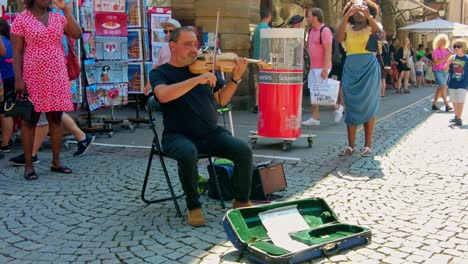 Älterer-Mann-Sitzt-Auf-Einem-Stuhl-Und-Spielt-Geige-Auf-Dem-Marktplatz-In-Straßburg