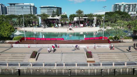 Imágenes-Aéreas-De-South-Bank,-South-Brisbane,-Tomadas-Al-Mediodía,-Con-La-Playa-De-South-Bank,-Zonas-Verdes-Y-El-Río-Brisbane.